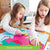 A customer photo of 2 young girls putting together the Asia Geo Puzzle. They both have their right hand stretched out over the puzzle on the table, putting a piece in place. There is a living room in the background.