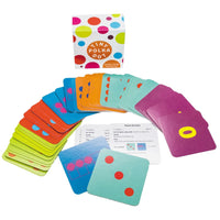 Tiny Polka Dots card game set spread out. In the back is the small, white, square box with colored polka dots all over. In front of the box are all the game cards fanned out. The cards are in a variety of colors, including; bright green, red, blue, orange, turquoise, and purple. Some cards have dot, looking like dice. And other cards have numbers printed on them. There are 2 cards at the bottom placed over the white instruction cards.