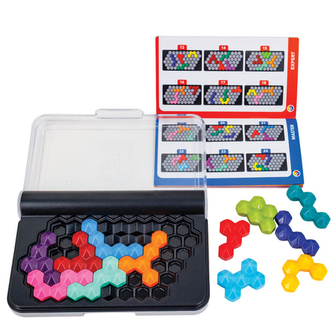 The I Q Six Pro game laid out with pieces and instructions. The game case / board has a grid of hexagon shapes on the top of black plastic with a hinged clear lid. There are several pieces, in many colors, placed on the board and several off to the right. The pieces are hexagons stuck together to form random shaped pieces, like Tetris pieces. In the upper-right, slightly under the clear lid is the instruction booklet, open to show challenges.  